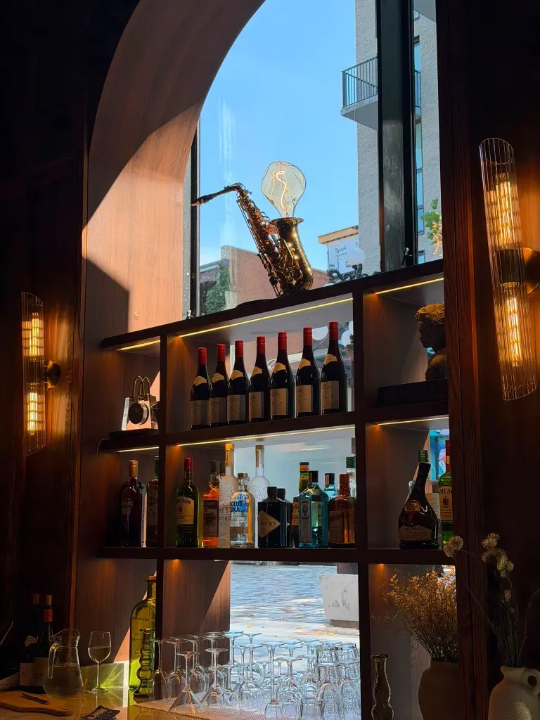 Entrecôte bar shelves with bottles, glassware, and warm wall lights